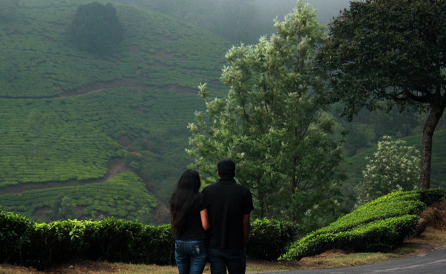 Honeymoon Couple in a beautiful tea estate posing for a photo during their honeymoon package in Kerala
